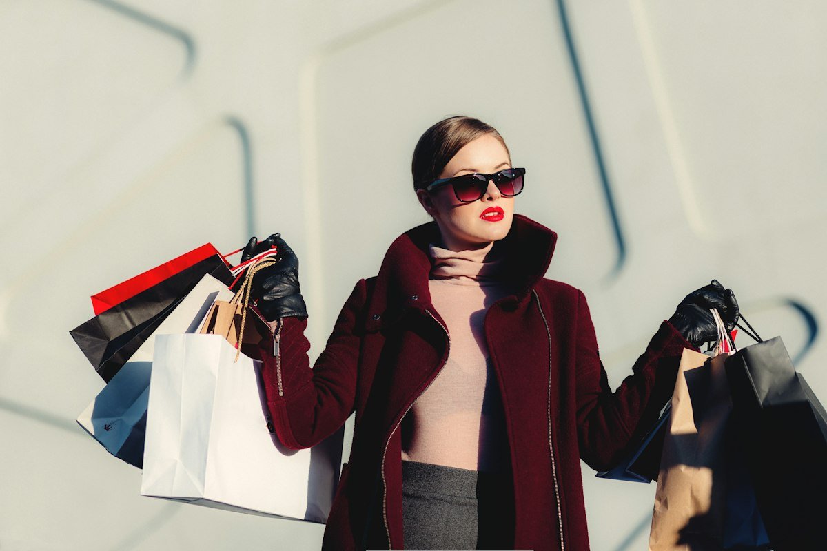 Woman in a burgundy coat carrying shopping bags
