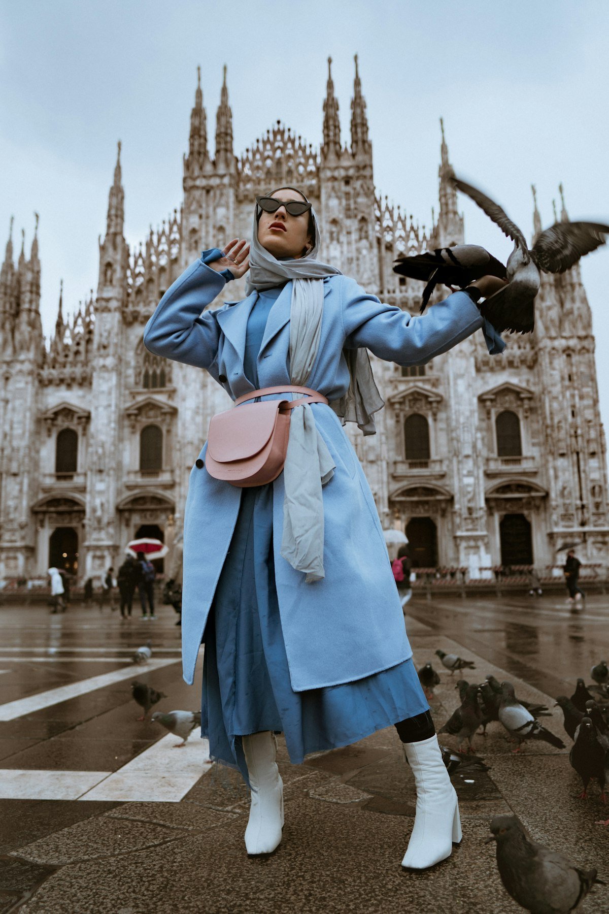 Woman in a light blue layered coat outfit in a city square